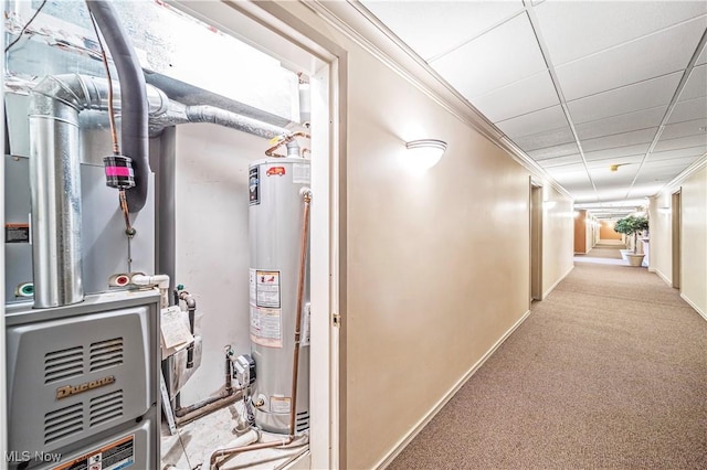 corridor with heating unit, gas water heater, light carpet, ornamental molding, and a drop ceiling