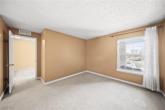 unfurnished room with light colored carpet and a textured ceiling