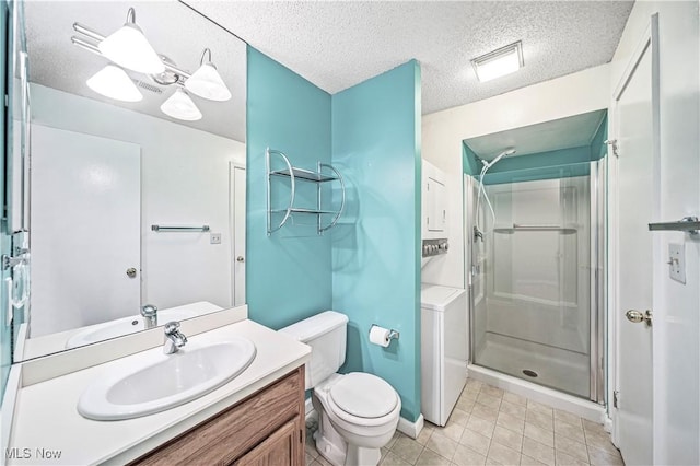 bathroom featuring a shower with shower door, washer / dryer, vanity, toilet, and a textured ceiling