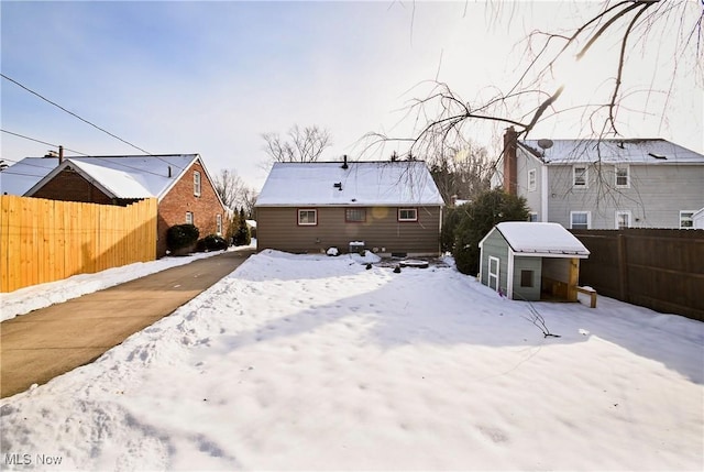 snow covered rear of property featuring a shed