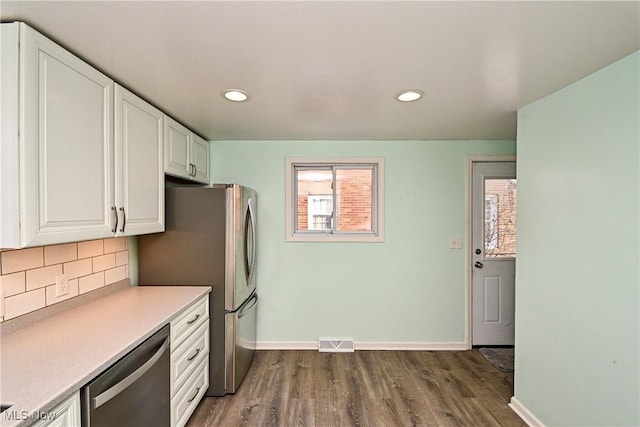 kitchen featuring tasteful backsplash, appliances with stainless steel finishes, dark wood-type flooring, and white cabinets