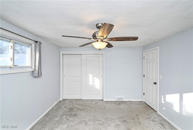 unfurnished bedroom with light colored carpet, ceiling fan, and a closet