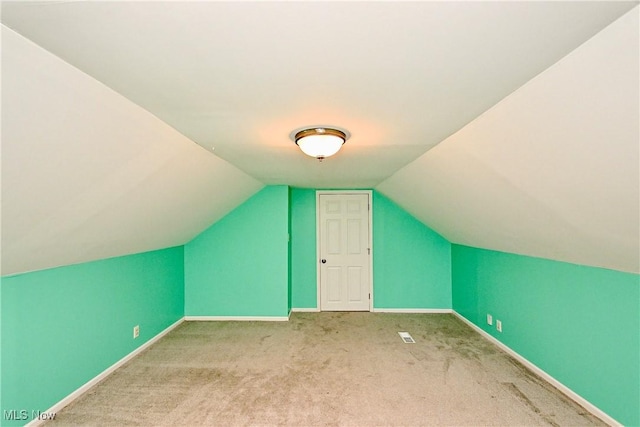 additional living space featuring light colored carpet and lofted ceiling