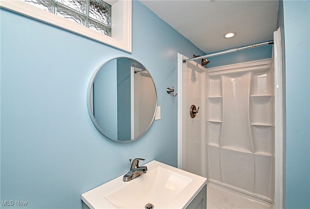 bathroom featuring walk in shower and vanity