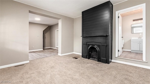 unfurnished living room with light carpet and a large fireplace