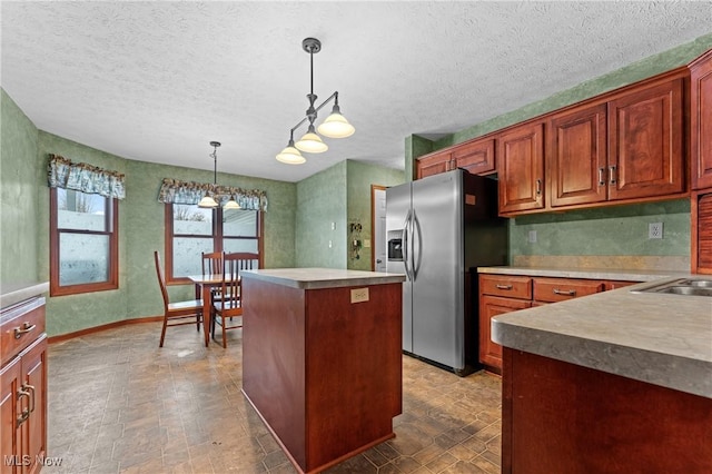 kitchen featuring a center island, stainless steel fridge with ice dispenser, hanging light fixtures, and a textured ceiling