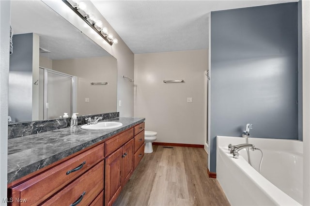 full bathroom with toilet, wood-type flooring, separate shower and tub, a textured ceiling, and vanity