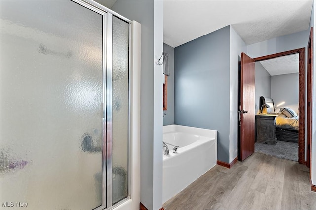 bathroom with hardwood / wood-style flooring, a textured ceiling, and separate shower and tub