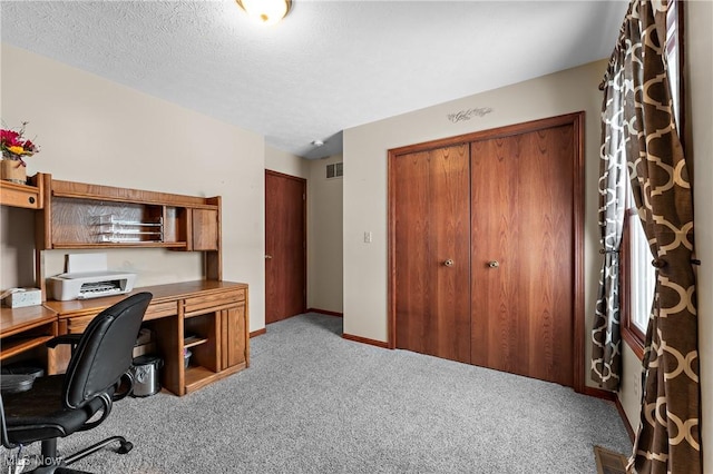 carpeted home office featuring a textured ceiling