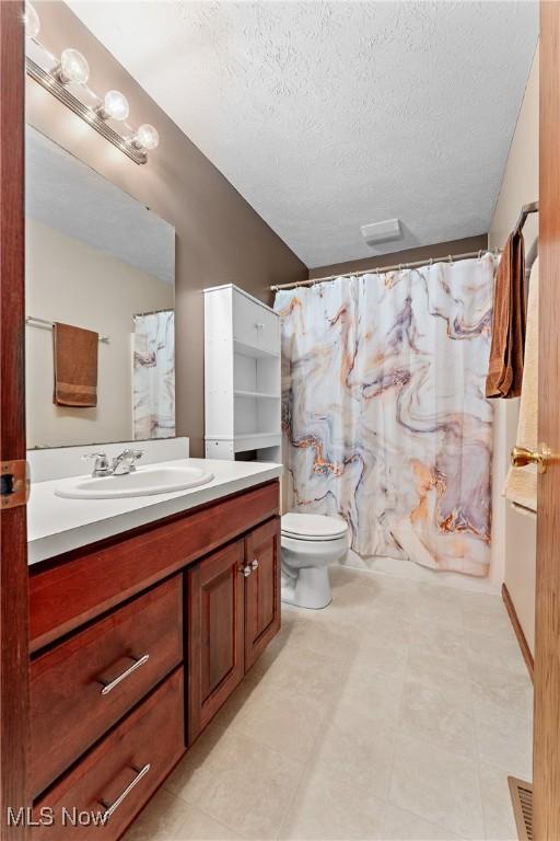 full bathroom featuring vanity, shower / bath combo, a textured ceiling, and toilet