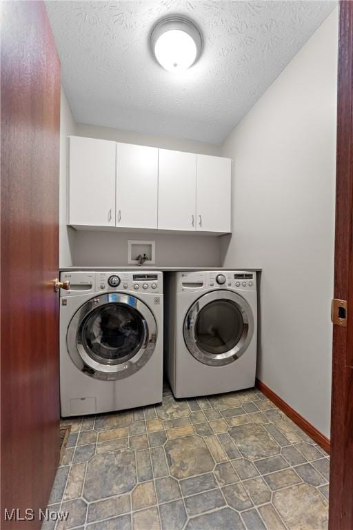 laundry room with cabinets, separate washer and dryer, and a textured ceiling