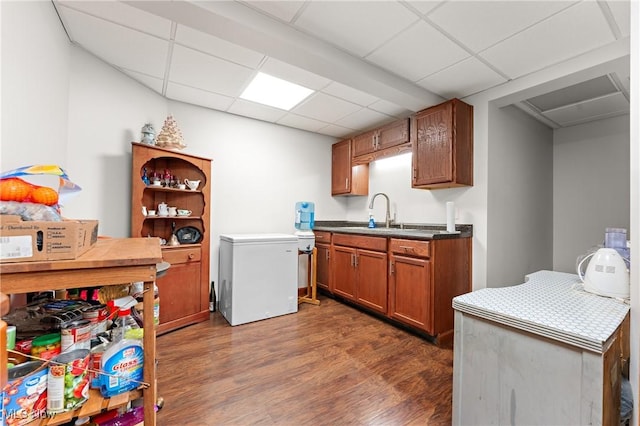 kitchen with dark hardwood / wood-style floors, sink, a drop ceiling, and refrigerator