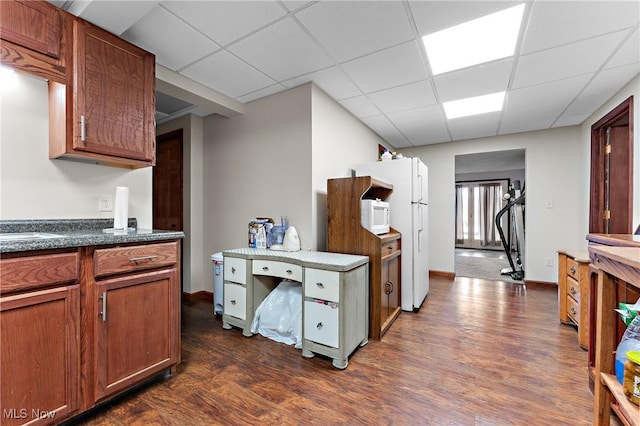 kitchen featuring dark hardwood / wood-style flooring, white appliances, and a paneled ceiling