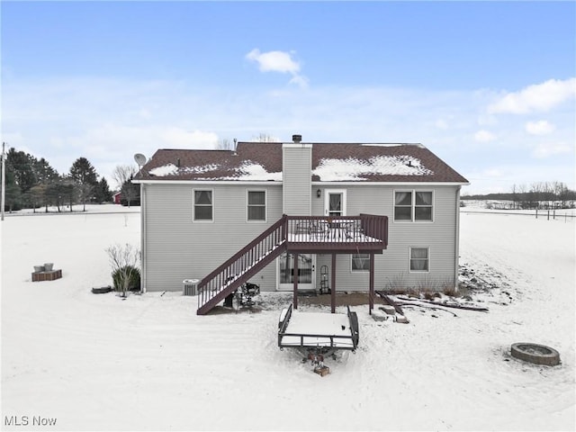 snow covered property with central AC, an outdoor fire pit, and a deck