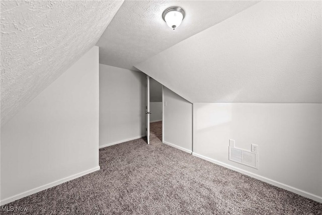 additional living space featuring vaulted ceiling, a textured ceiling, and carpet flooring