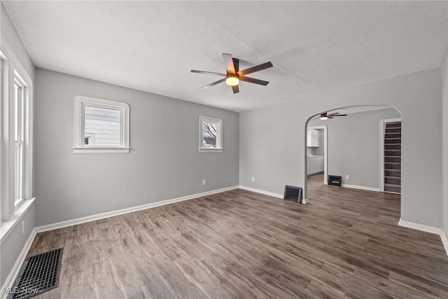 spare room with ceiling fan, plenty of natural light, dark hardwood / wood-style floors, and a textured ceiling