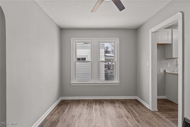 unfurnished dining area featuring a textured ceiling, ceiling fan, and light hardwood / wood-style floors