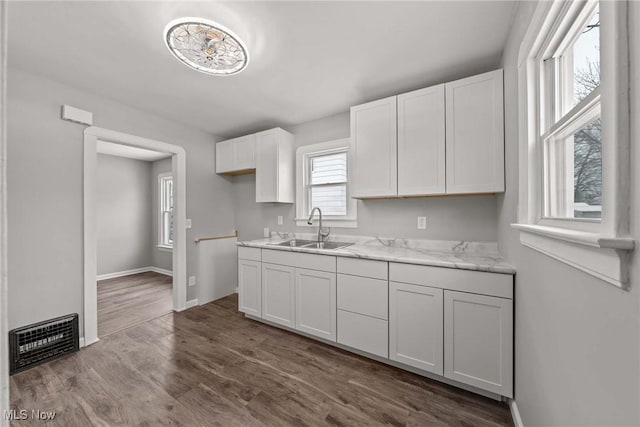 kitchen featuring light stone countertops, sink, hardwood / wood-style floors, and white cabinets