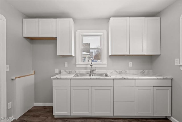 kitchen with white cabinetry, sink, light stone counters, and dark hardwood / wood-style floors