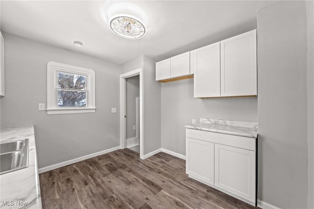 kitchen featuring white cabinetry, sink, light stone counters, and dark hardwood / wood-style floors