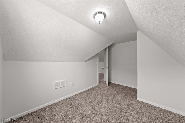 bonus room featuring carpet flooring, vaulted ceiling, and a textured ceiling