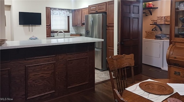 kitchen featuring tasteful backsplash, sink, stainless steel fridge, dark hardwood / wood-style flooring, and washing machine and clothes dryer