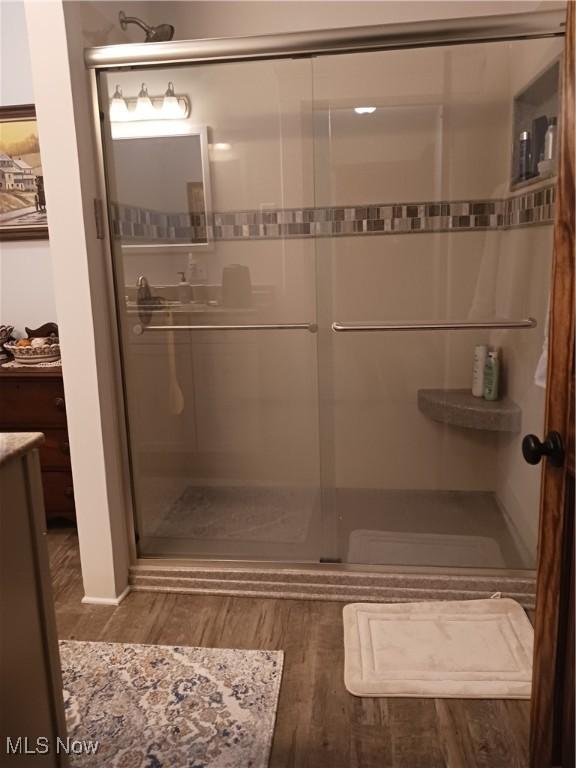 bathroom with an enclosed shower, vanity, and wood-type flooring