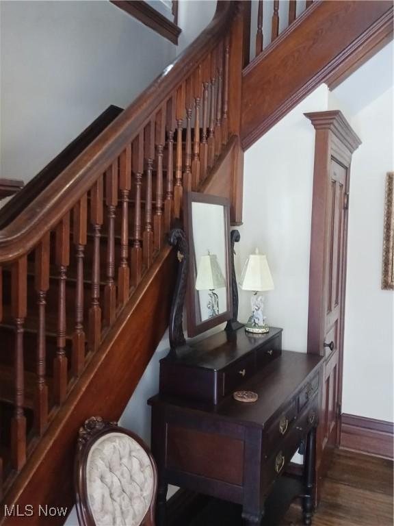 stairway with decorative columns and hardwood / wood-style flooring