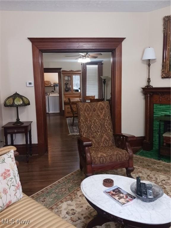 living room featuring a tile fireplace, dark hardwood / wood-style floors, washing machine and clothes dryer, and ceiling fan