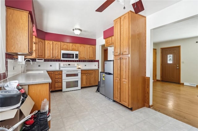 kitchen featuring sink, white appliances, ceiling fan, and backsplash