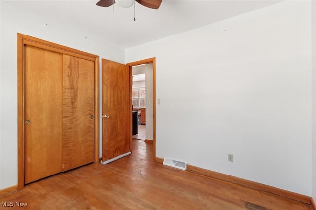 unfurnished bedroom with light hardwood / wood-style flooring, ceiling fan, and a closet