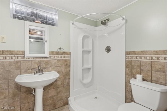 bathroom featuring walk in shower, toilet, and tile walls