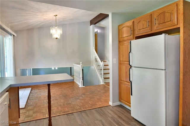 kitchen featuring white appliances, a notable chandelier, hanging light fixtures, and light hardwood / wood-style flooring