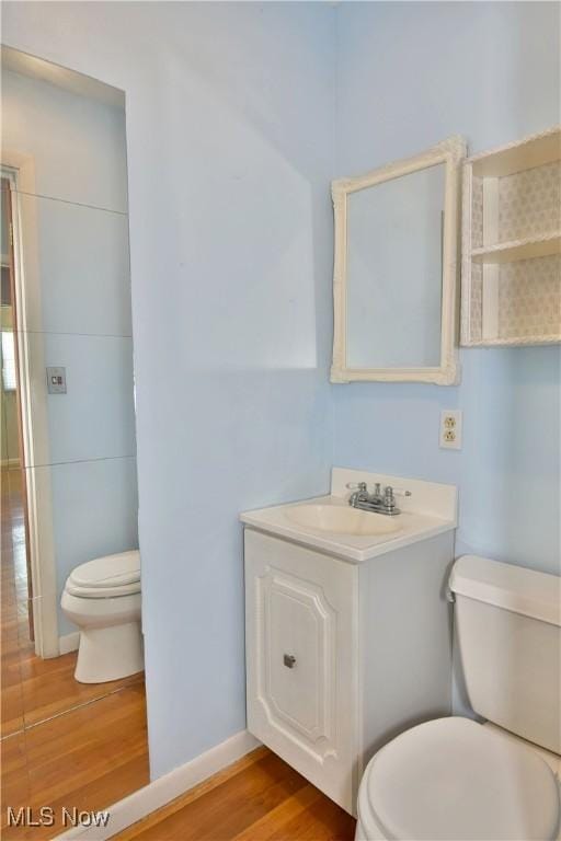 bathroom with hardwood / wood-style flooring, vanity, and toilet