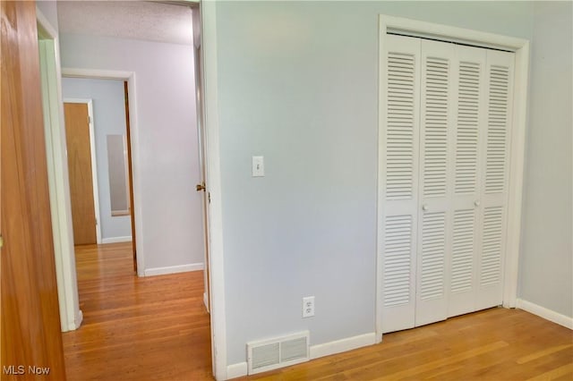 unfurnished bedroom featuring light hardwood / wood-style floors, a closet, and a textured ceiling