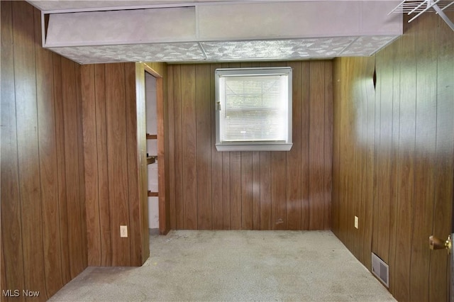 carpeted empty room with wood walls