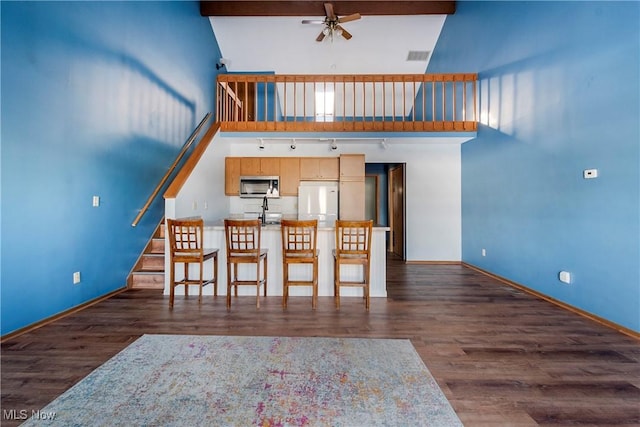 unfurnished dining area featuring a high ceiling, ceiling fan, and dark hardwood / wood-style flooring