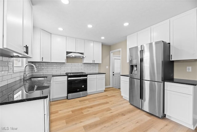 kitchen with sink, white cabinets, stainless steel appliances, light hardwood / wood-style floors, and backsplash