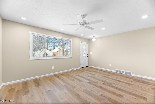 interior space featuring ceiling fan, light hardwood / wood-style floors, and a textured ceiling