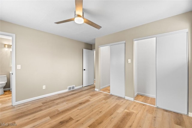 unfurnished bedroom featuring multiple closets, connected bathroom, ceiling fan, and light hardwood / wood-style flooring