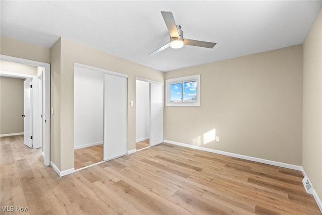 unfurnished bedroom featuring two closets, ceiling fan, and light wood-type flooring