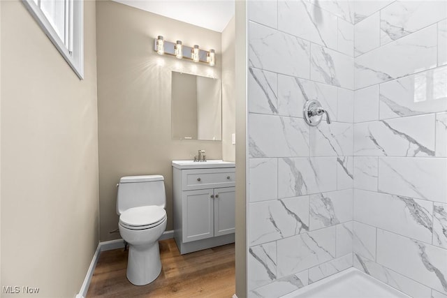 bathroom featuring vanity, hardwood / wood-style flooring, toilet, and tiled shower