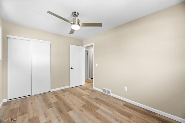 unfurnished bedroom featuring ceiling fan, a closet, and light wood-type flooring