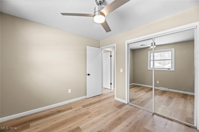 unfurnished bedroom with light hardwood / wood-style floors, a closet, and ceiling fan