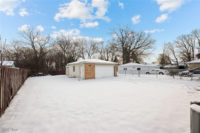 snowy yard featuring a garage and an outdoor structure