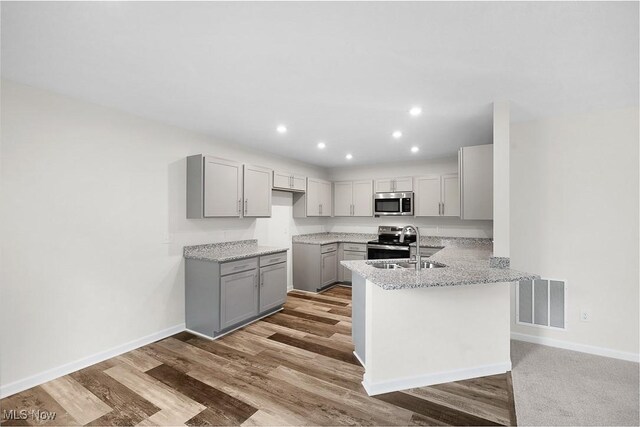 24326 Mastick Rd, North Olmsted, OH 44070 - kitchen with appliances with stainless steel finishes, gray cabinetry, a peninsula, light wood-style floors, and baseboards