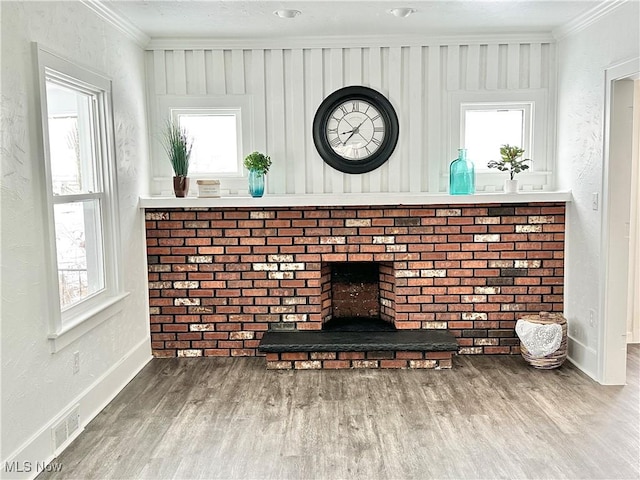 interior details with ornamental molding, hardwood / wood-style floors, and a brick fireplace