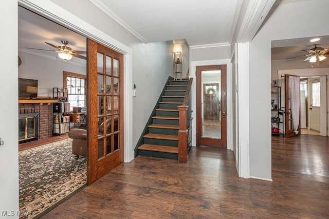 stairway with ornamental molding, a brick fireplace, a healthy amount of sunlight, and hardwood / wood-style floors