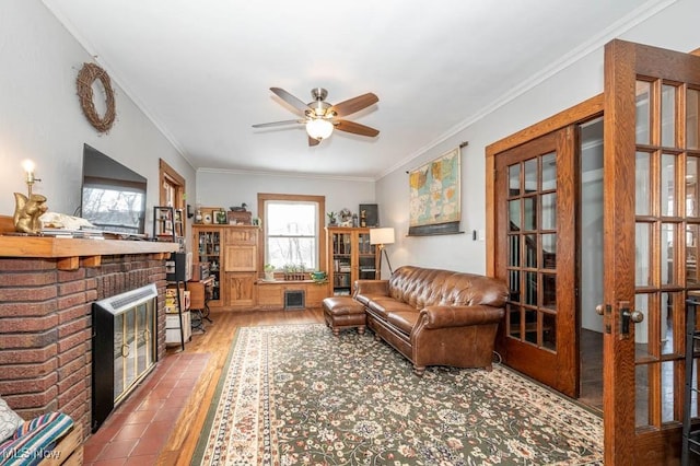 living room featuring crown molding, ceiling fan, wood-type flooring, and a fireplace