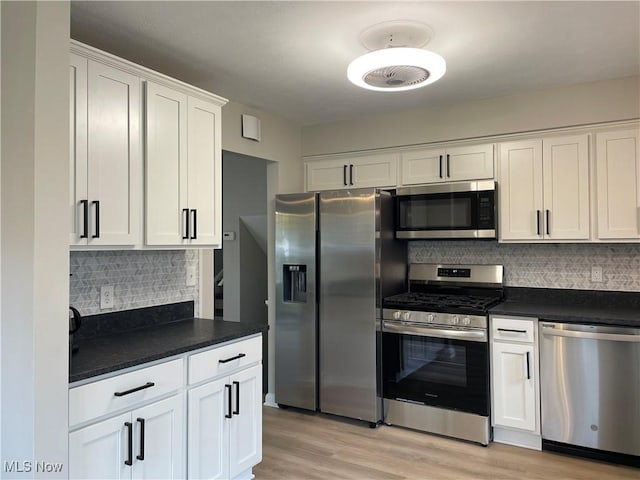 kitchen featuring stainless steel appliances, white cabinets, backsplash, and light hardwood / wood-style flooring